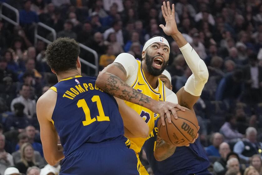 Los Angeles Lakers forward Anthony Davis, middle, is fouled by Golden State Warriors guard Klay Thompson.