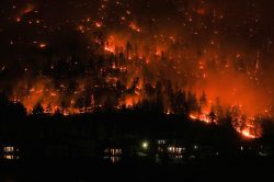 Flames encircle a mountainside above nearby homes as the McDougall Creek wildfire roared in West Kelowna, British Columbia, on Aug.Ê18. Extreme weather conditions fueled CanadaÕs worst wildfire season on record, with thousands of fires devastating millions of acres and darkening skies thousands of miles away.